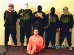 Nick Berg, in orange, seated, before his decapitation by the five men standing over him.